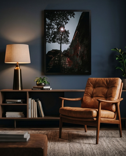 Sonnenstern in Baumkrone – Gerahmter Kunstdruck an dunkelblauer Wand über Holzregal mit Ledersessel, dunkles Wohnzimmer Lifestyle
