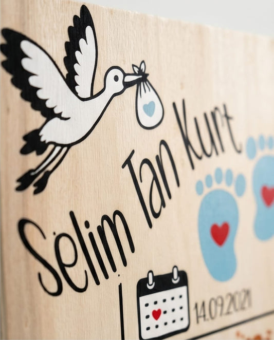Nahaufnahme mit Storch-Motiv, Babyfüßchen und individuellem Kindernamen in eleganter Handschrift
