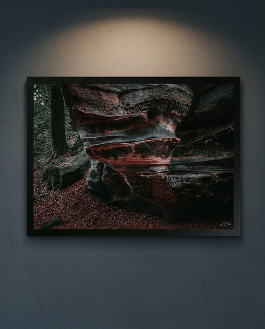 Der Lavafelsen – Gerahmter Kunstdruck an dunkelgrauer Wand mit Deckenstrahler, Querformat, roter Sandstein mit Wabenstruktur