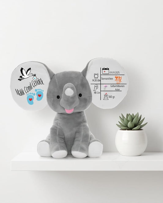 Grauer personalisierter Elefant Kuscheltier mit bedruckten Ohren auf einem weißen Regal, dekoriert mit einer Sukkulente – stilvolles Geschenk zur Geburt oder Taufe