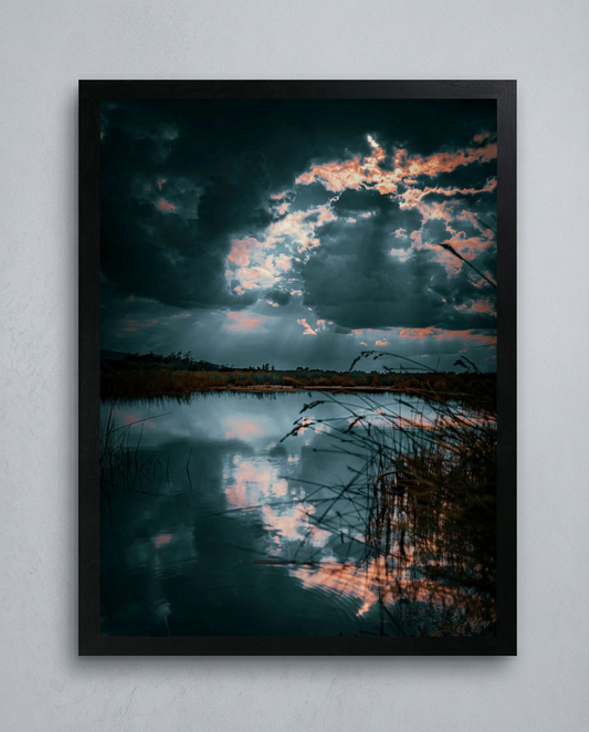 Stille vor dem Sturm – Gerahmter Kunstdruck an hellgrauer Wand, Hochformat, türkis-rosa Gewitterwolken über See