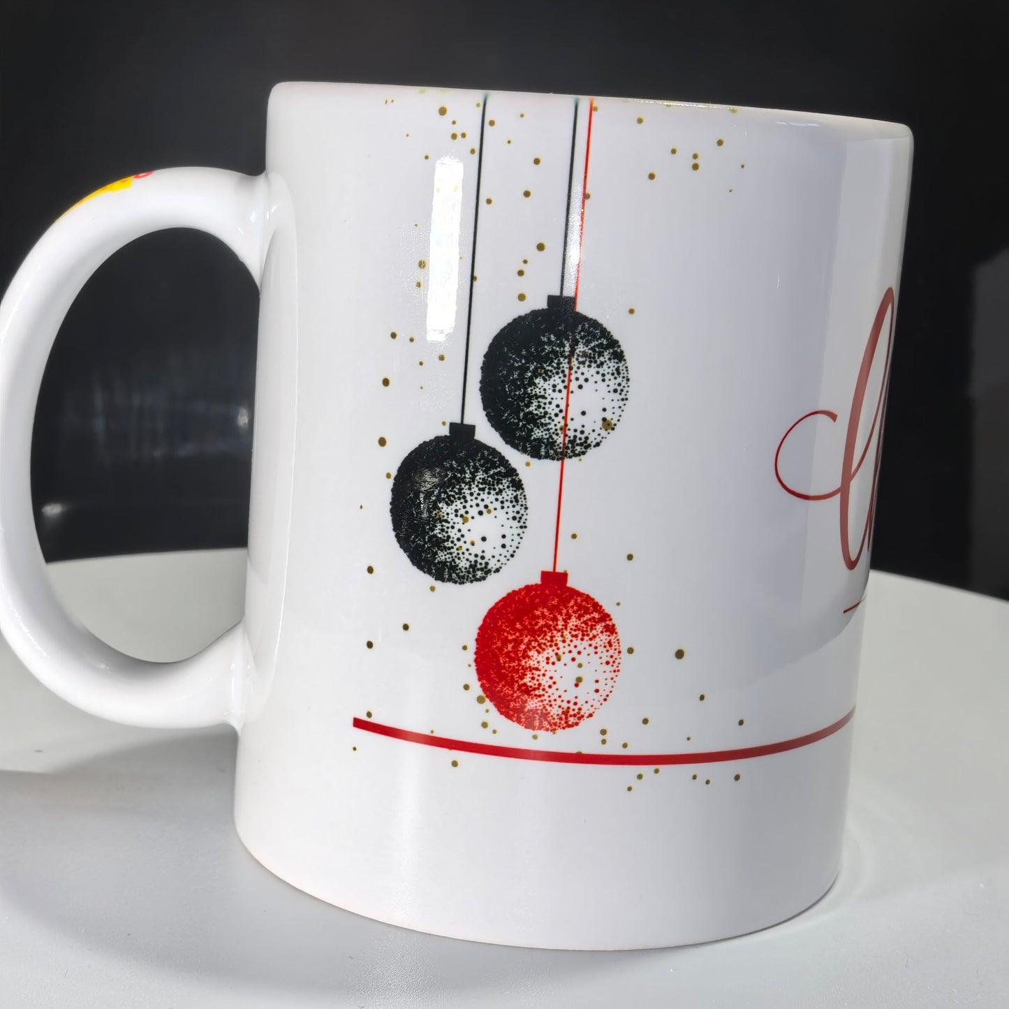 Weihnachtstasse mit festlichem Aufdruck von drei schwarzen und roten Weihnachtskugeln.
